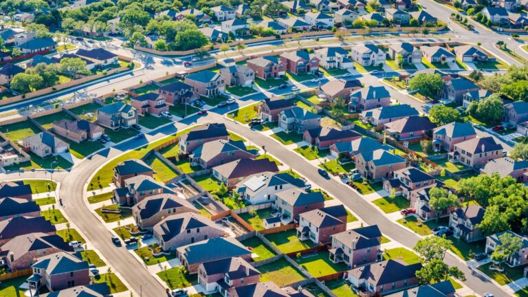 Aerial view of a suburban neighborhood of single-family homes along curving, tree-lined streets